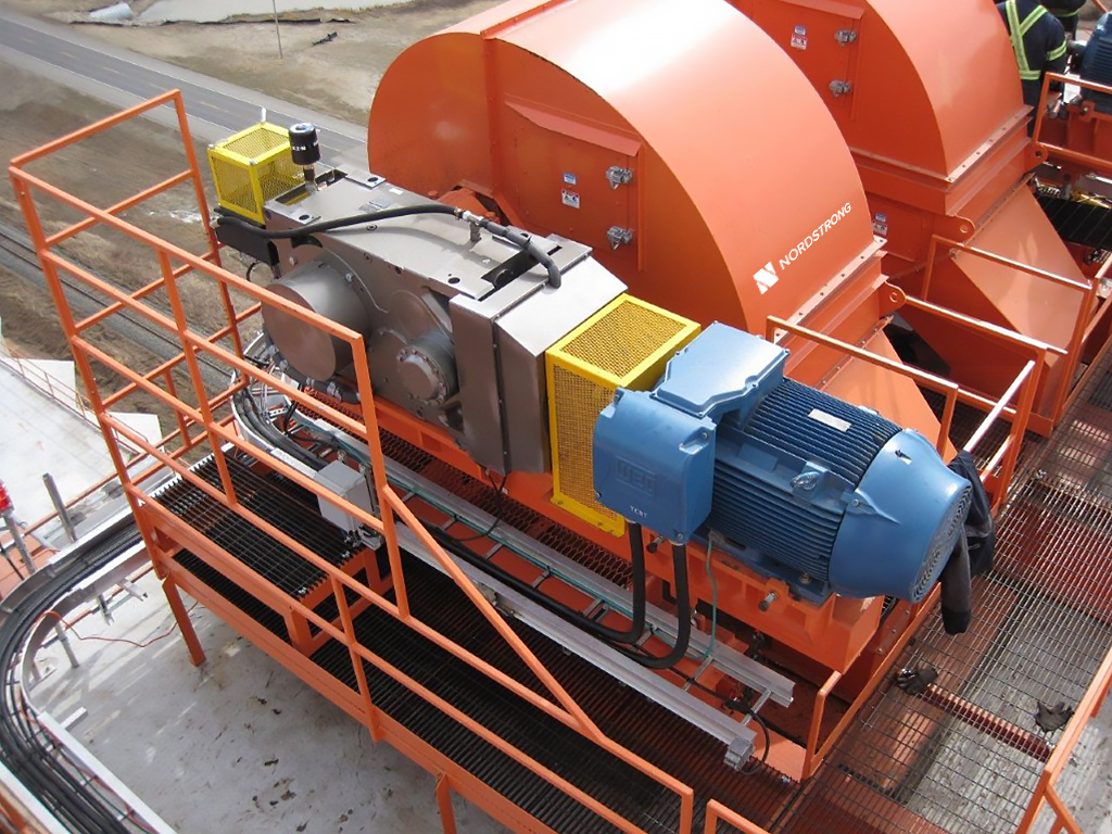 Green bucket elevator head section with Nordstrong Equipment label, installed outdoors on a metal platform.