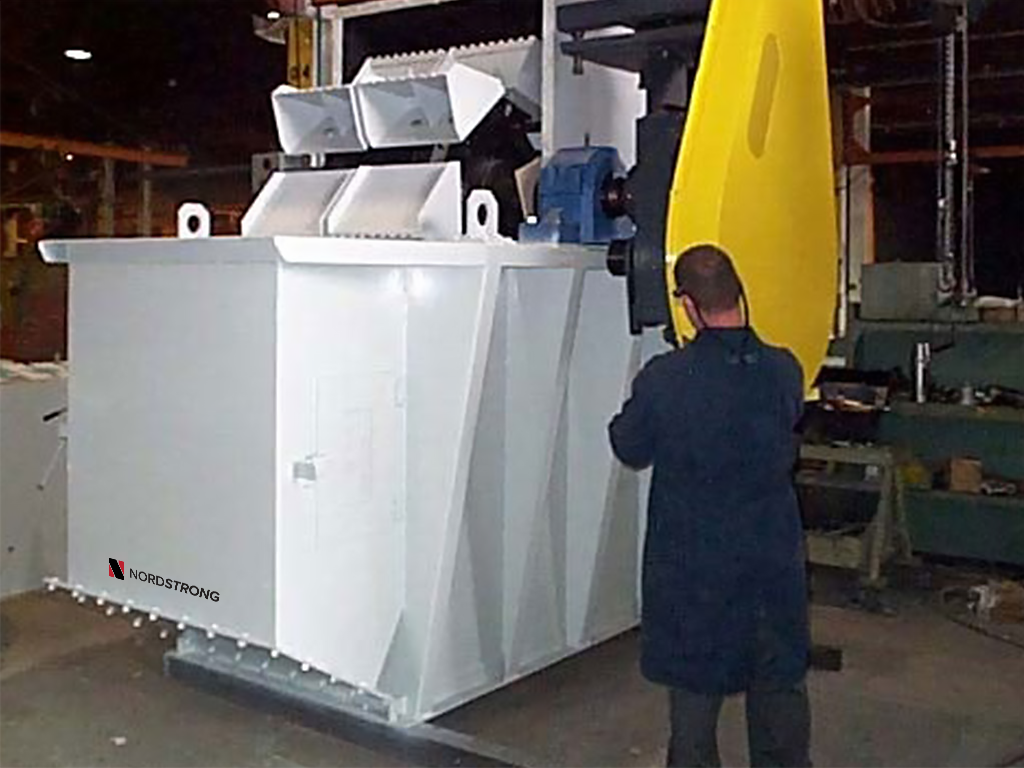Industrial bucket elevator with white body and yellow motor cover, with a worker standing nearby inside a facility.