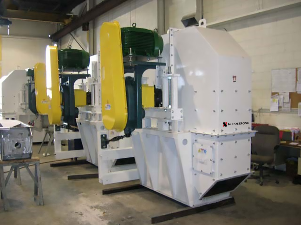 Industrial bucket elevator heads with white bodies and yellow motor covers, lined up inside a warehouse.
